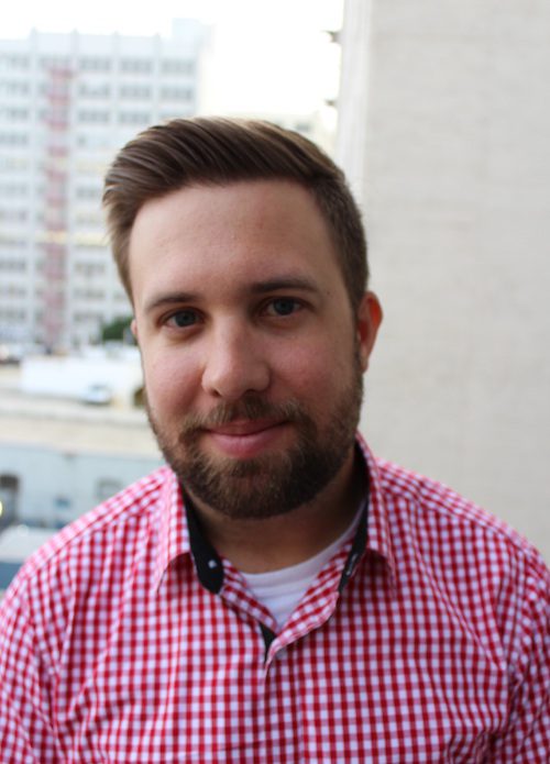 Man smiling at camera and wearing a red and white button up top