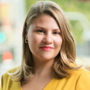 Sarah Hooper, executive director of the UCSF/UC Law SF Consortium on Law, Science & Health Policy, poses for a photo outdoors, wearing a yellow top and smiling.