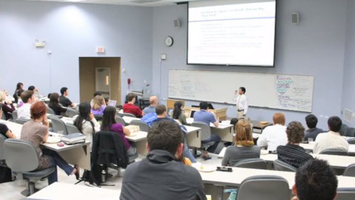 A professor lecturing to a classroom full of students.