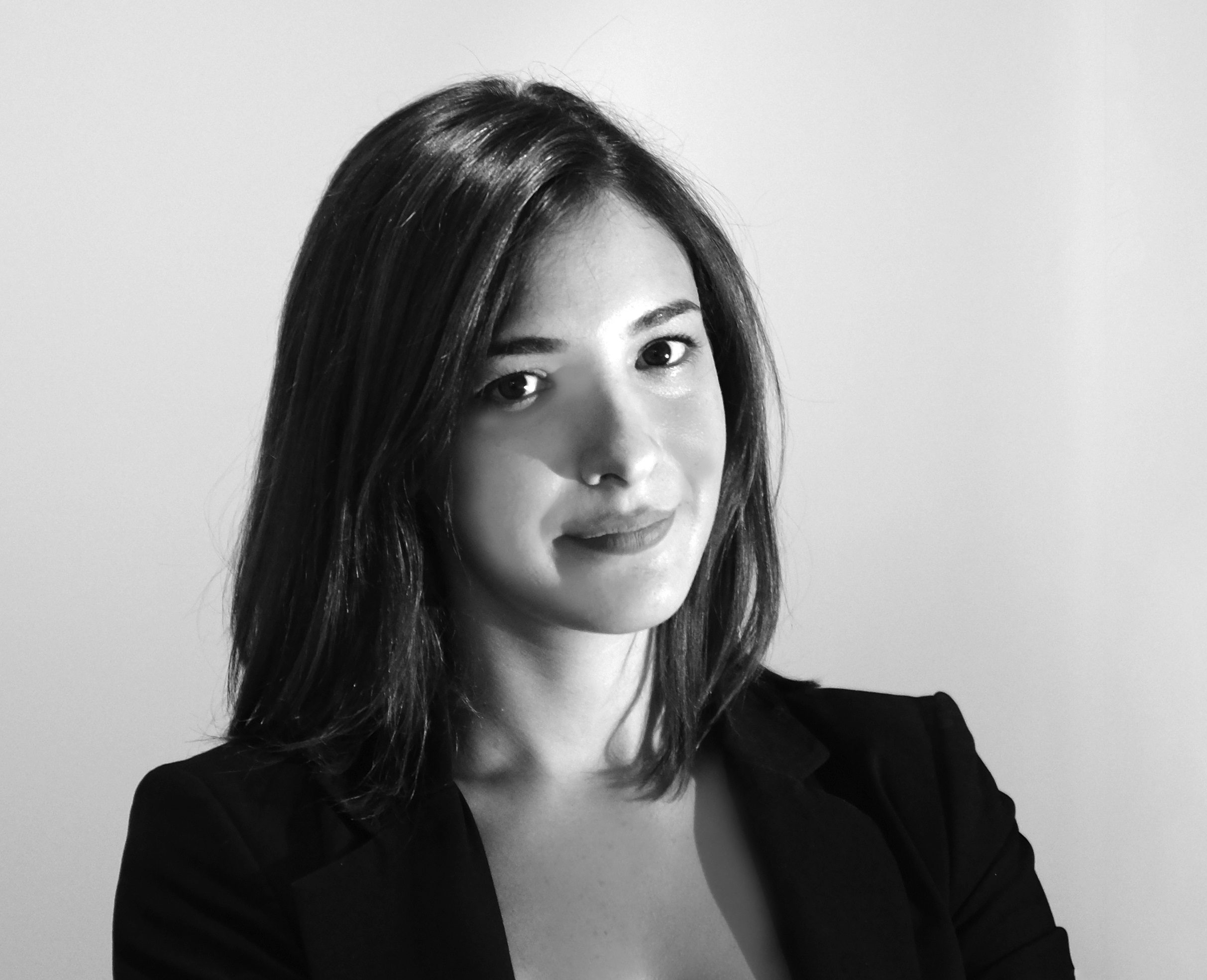 Black and white photo of a woman smiling and looking at the camera, wearing a black suit jacket