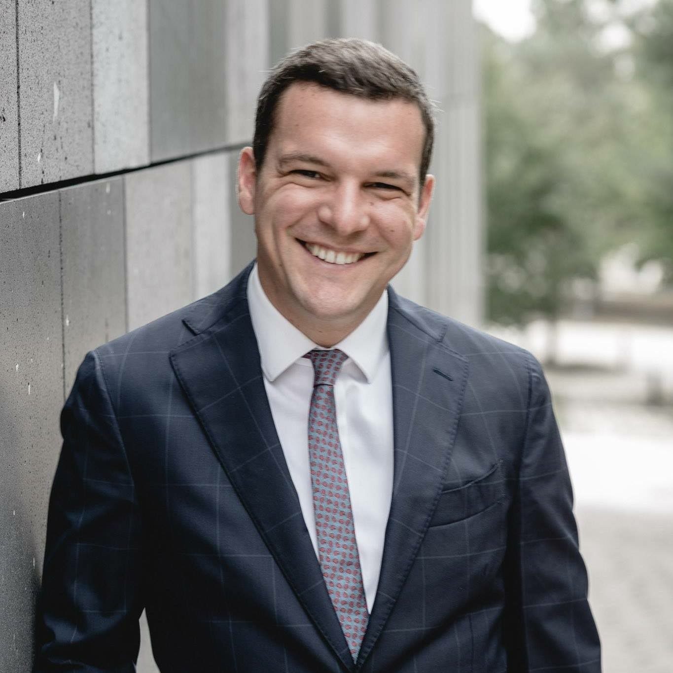 Man smiling and looking at the camera, wearing a suit and tie