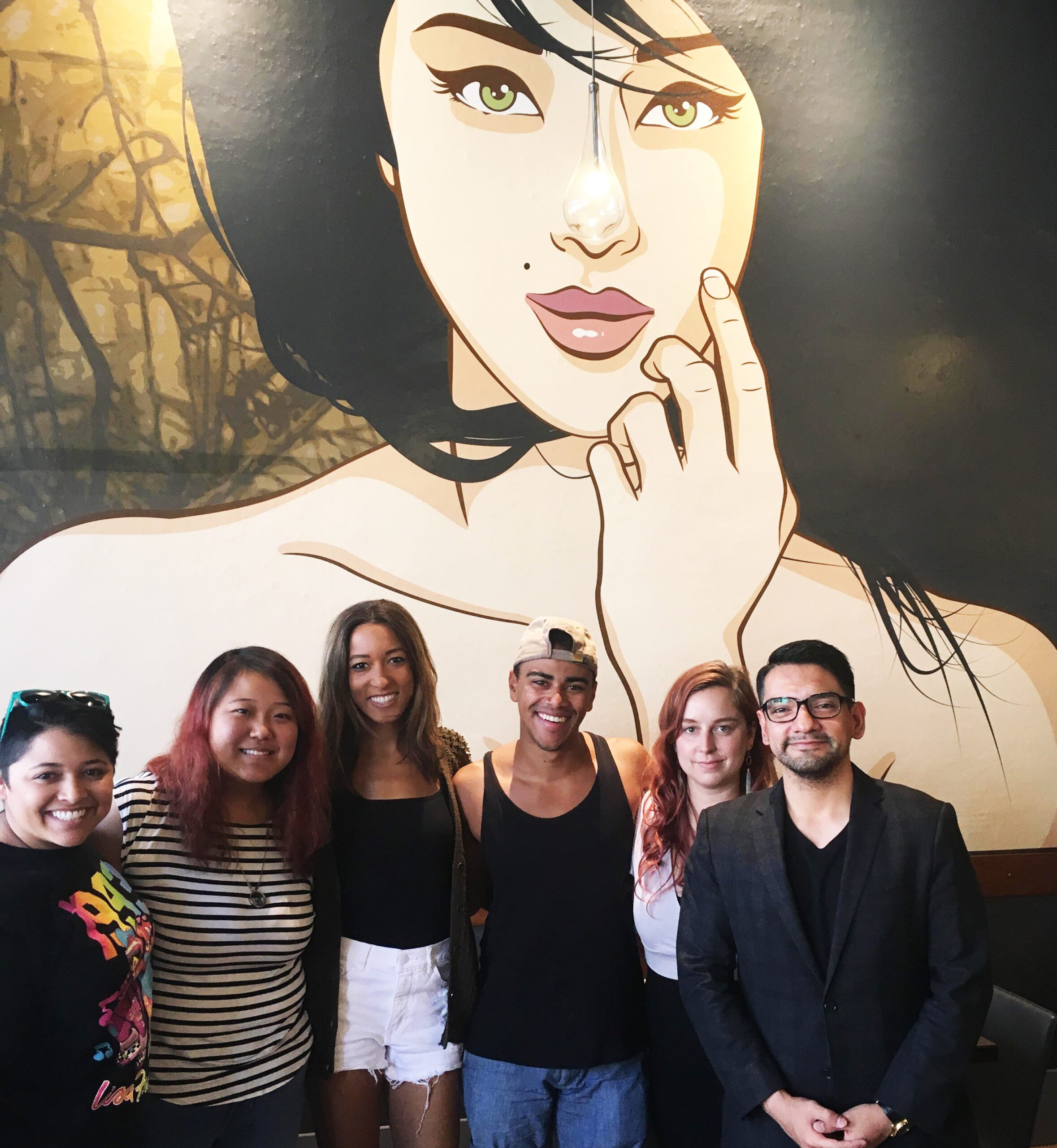 Students standing in front of mural inside restaurant