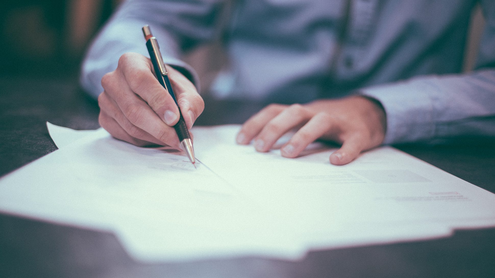 Hand holding a pen writing on paper