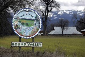 Welcome sign for Round Valley, featuring "Nature's Hideaway" and illustrations of wildlife, set against a backdrop of fields and mountains.