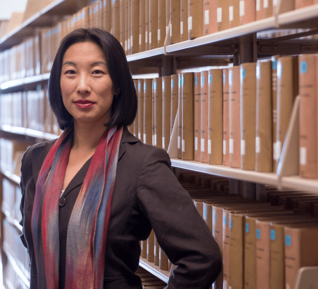 Ming Hsu Chen standing in front of bookshelves