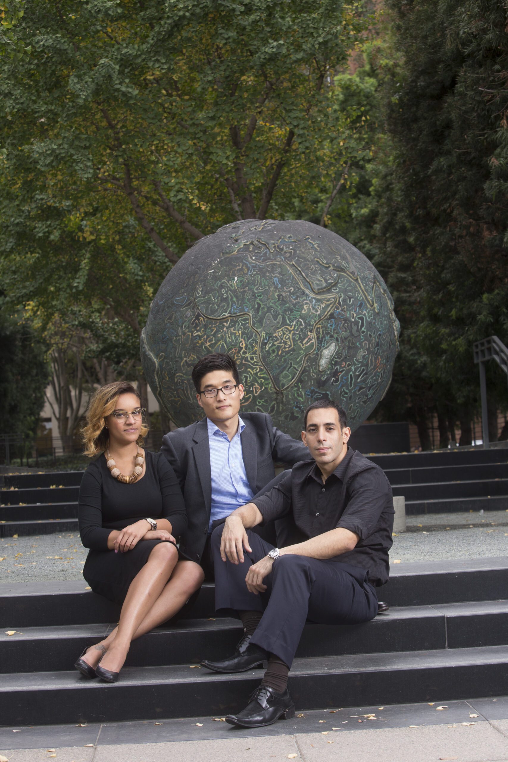 Three people sitting on stairs and looking at the camera