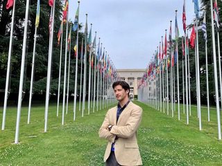 young law students stands in front of UN building in Geneva Switzerland surrounded by flags