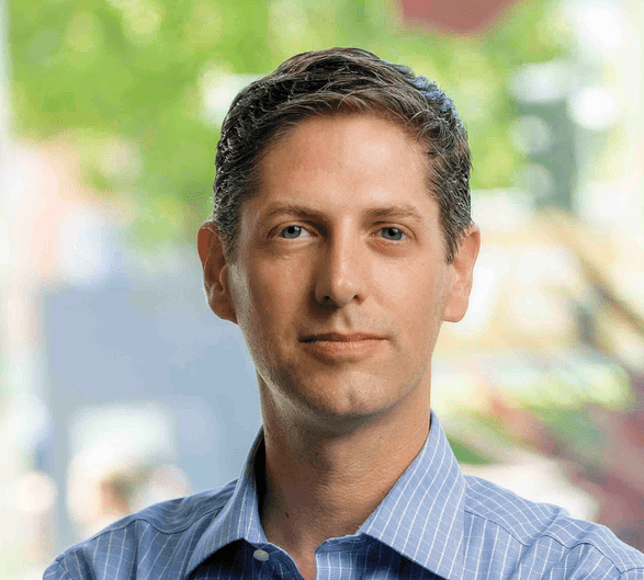 headshot of clean shaven man with brown hair, blue eyes and a button-up shirt