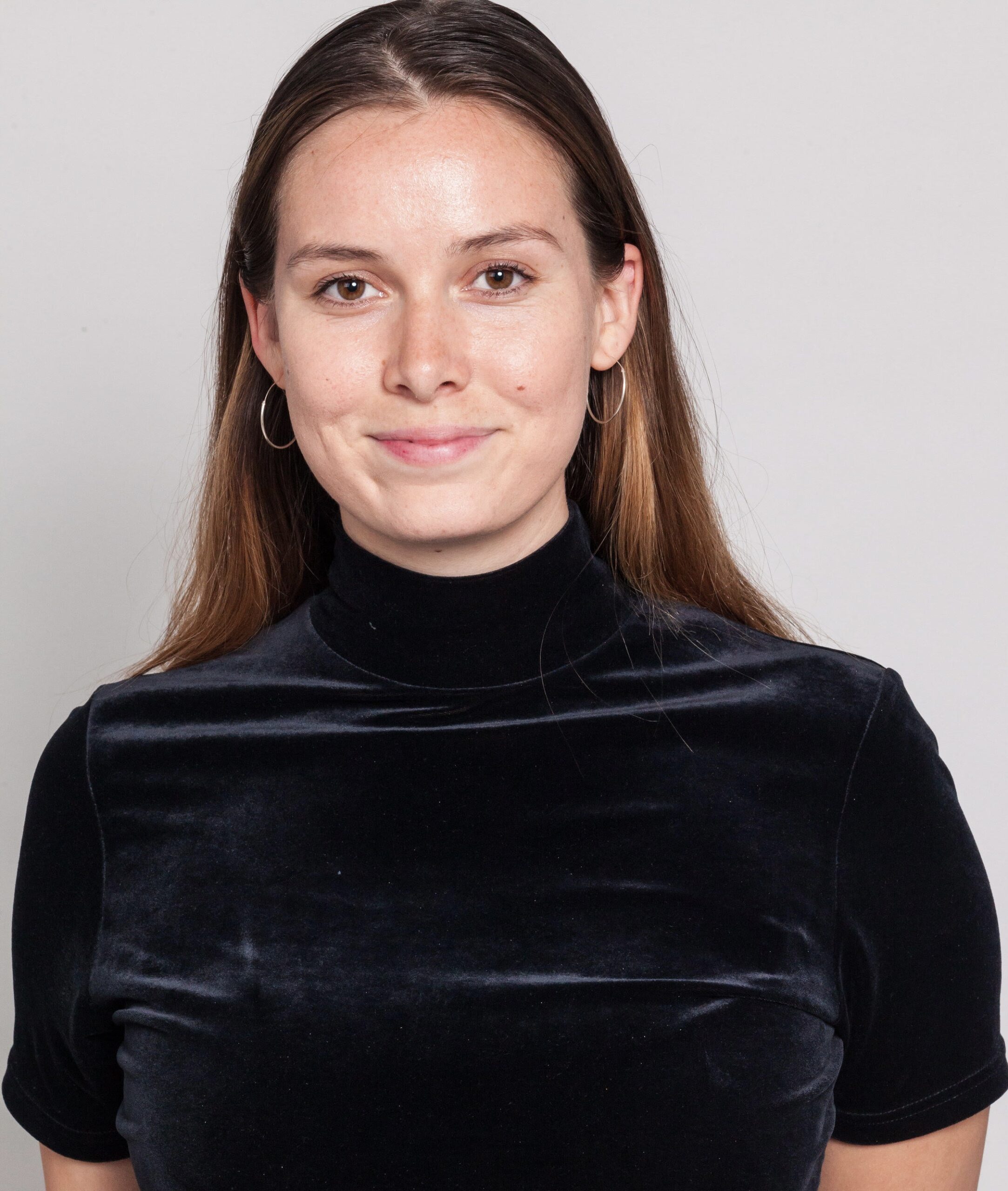 UC Law SF student Miranda Lockman, JD '25, smiling in a black velvet shirt against a light gray background.