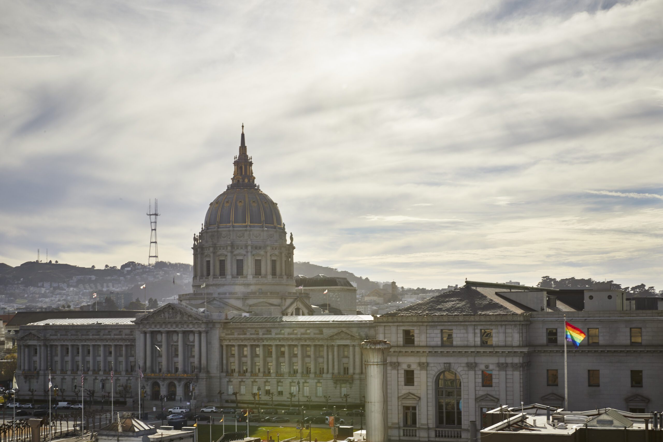 Aerial shot of dome building, SF city hall. Cloudy skies, sun shining in the backdrop