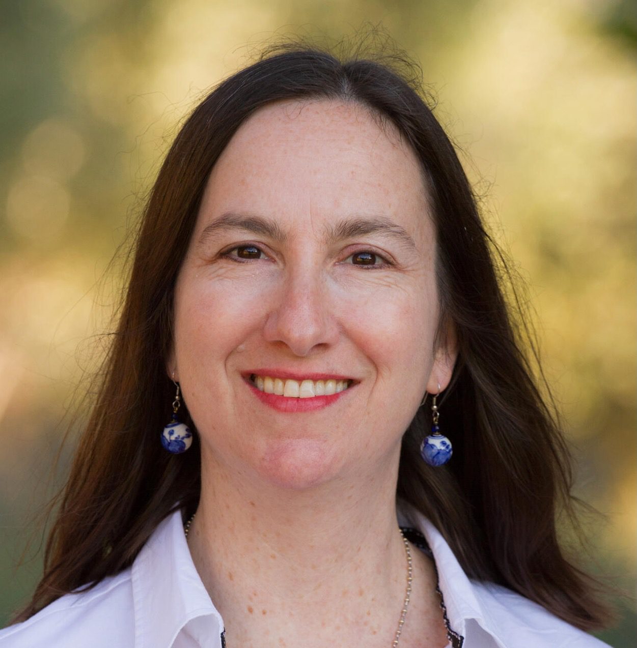 head shot of smiling white woman with dark hair and earings