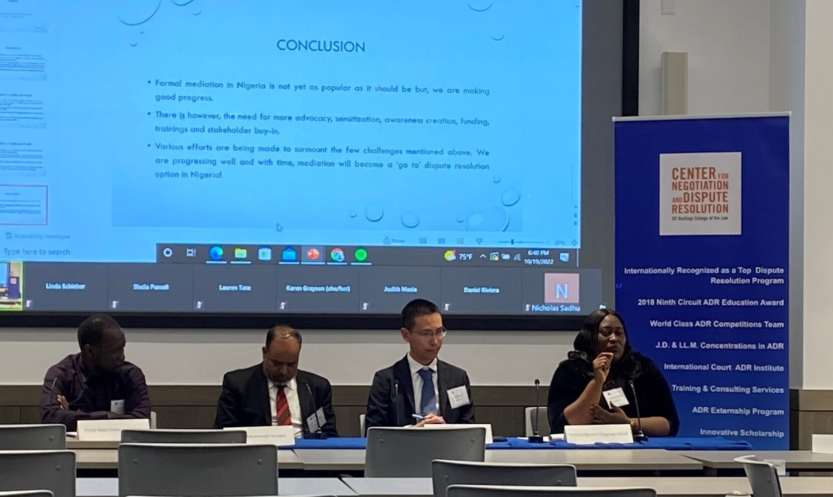 A panel discussion featuring four speakers on mediation developments, with a presentation slide in the background summarizing conclusions on mediation in Nigeria.