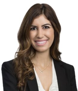 Natalie Alameddine smiles in a professional headshot, wearing a black blazer over a white top, against a plain background.