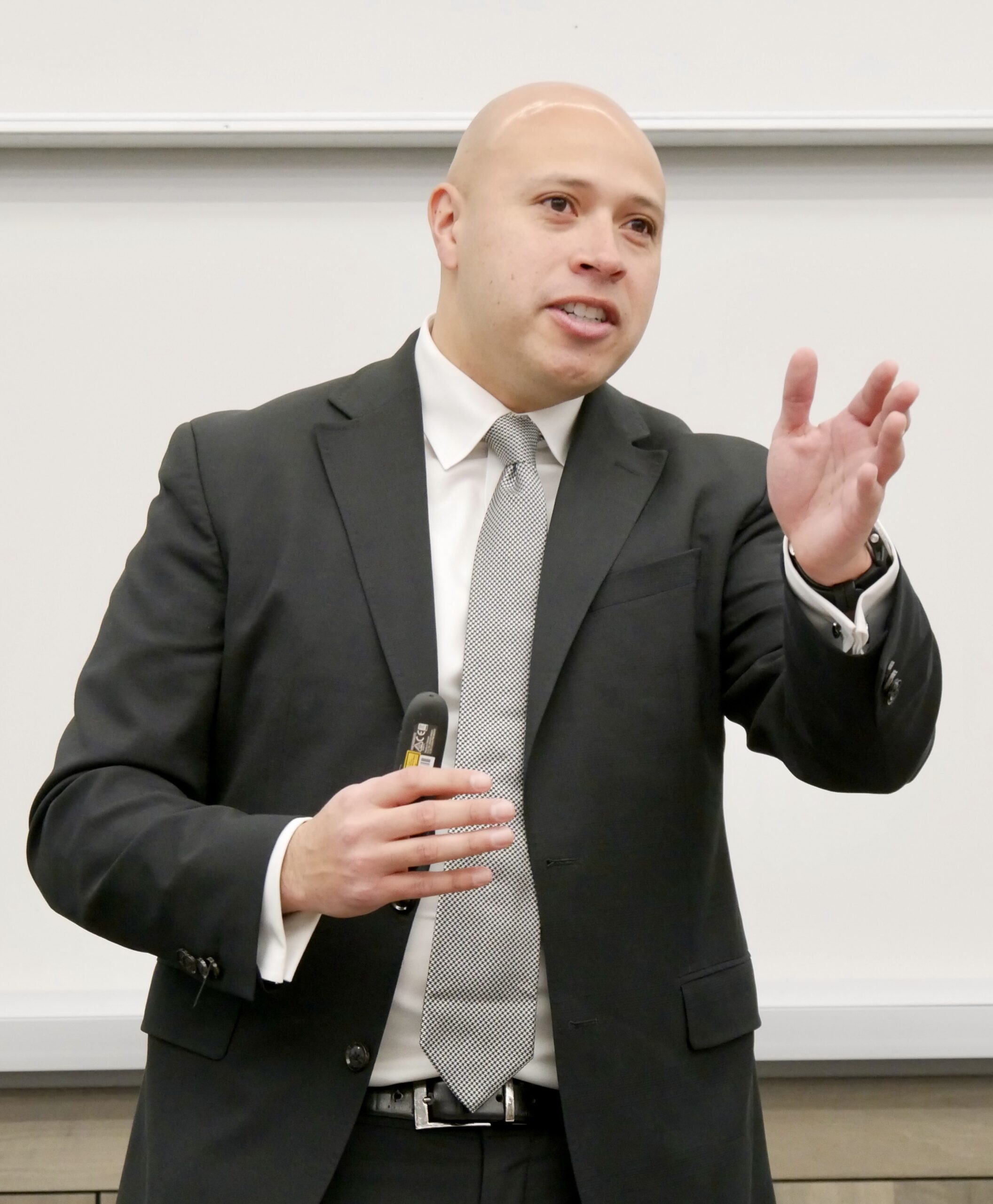 Director of Diversity, Equity, and Inclusion Mario Lopez '15 speaks at a campus DEI forum, gesturing as he discusses initiatives for an inclusive environment.