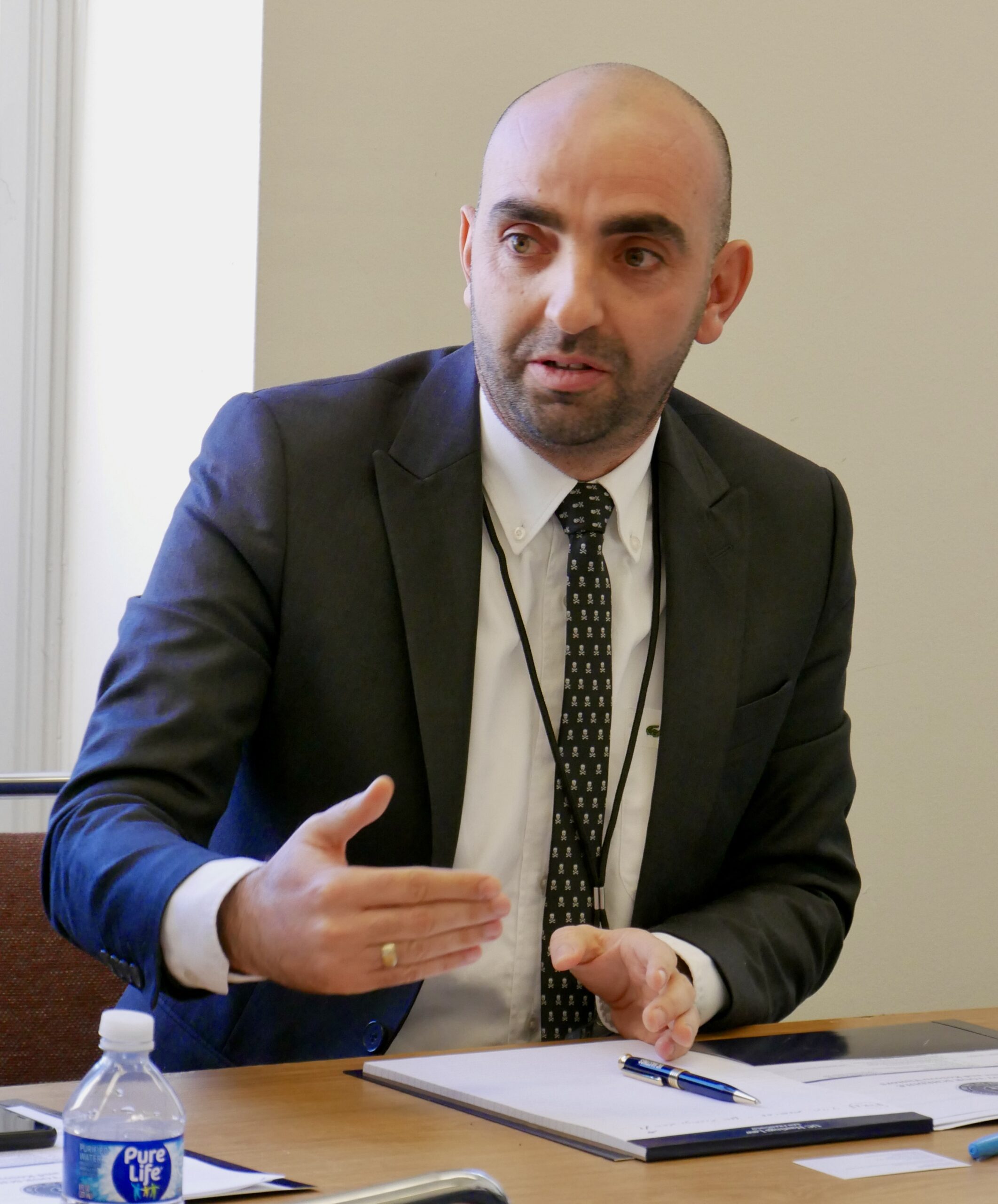 Professor Muhamet Vokrri from the University of Pristina in Kosovo is speaking during a meeting at UC Law San Francisco, gesturing with his hands.