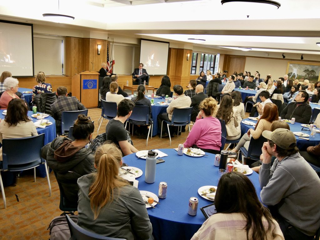 UC Law SF students, faculty, and staff attended a fireside chat featuring George Roberts '69 and Chancellor David Faigman, seated at a stage.