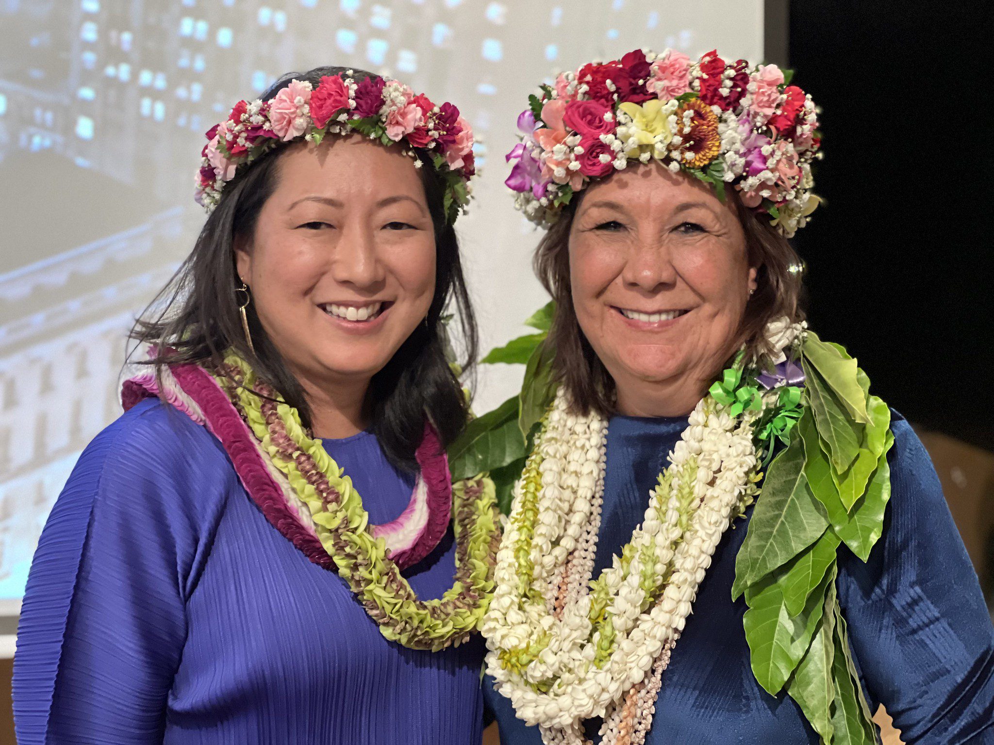 Ann Teranishi and Crystal Rose, wearing floral wreaths and leis, smile together at the UC Law San Francisco alumni gala in Hawaii, Fall 2022.