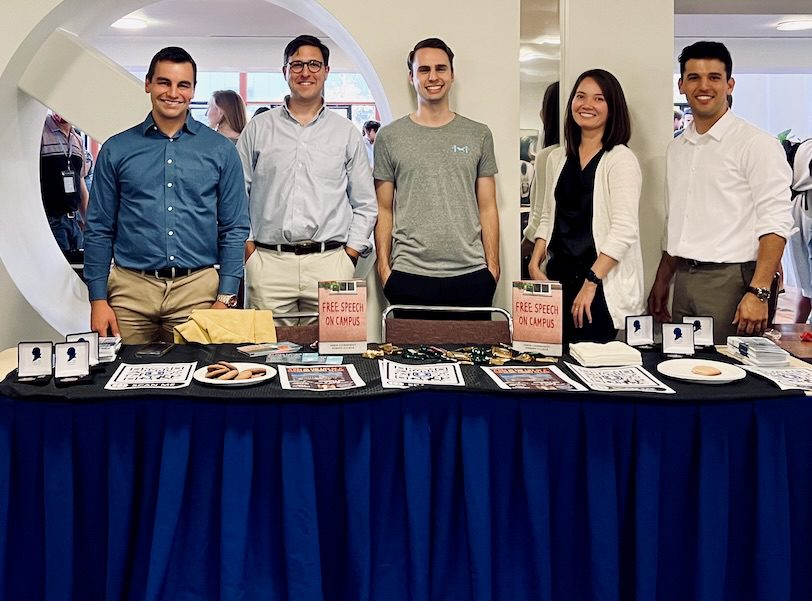 Members of the UC Law SF Chapter of the Federalist Society stand together at a student organization fair, showcasing their table with promotional materials.