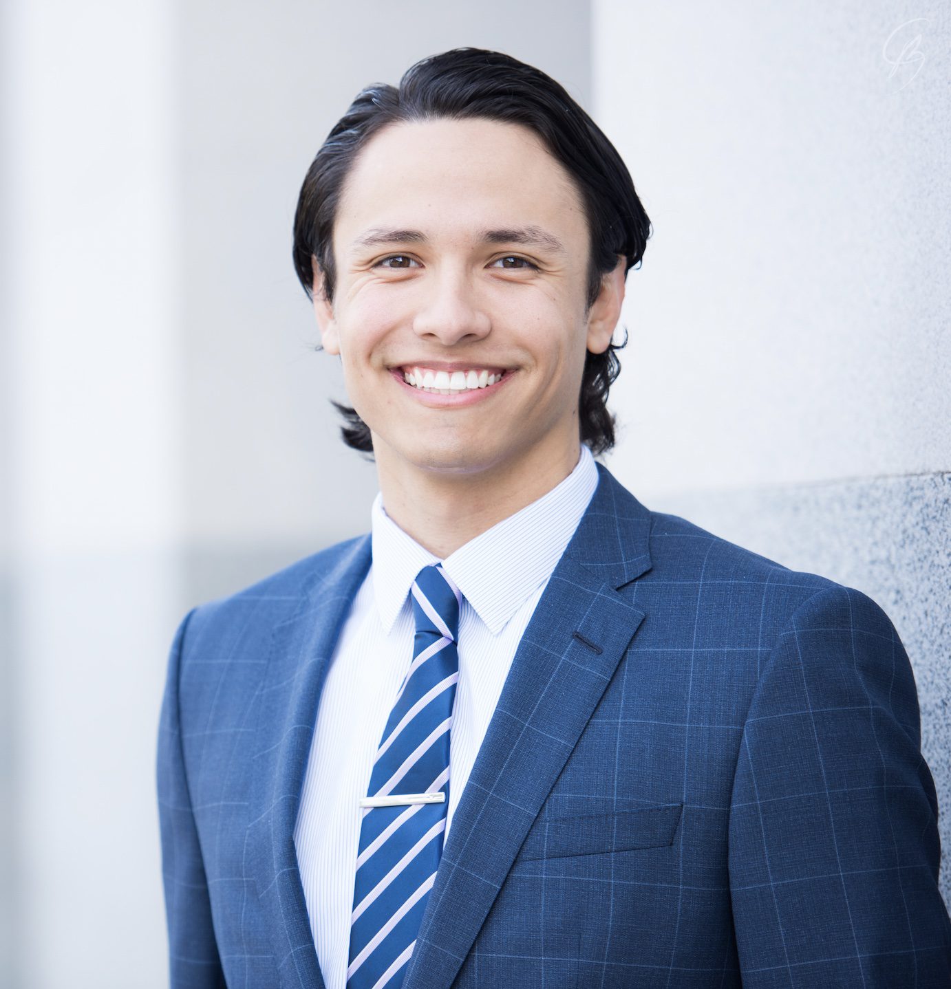 Victor Torres '25 smiles in a blue suit and striped tie against a light background, showcasing his professional appearance for a scholarship announcement.