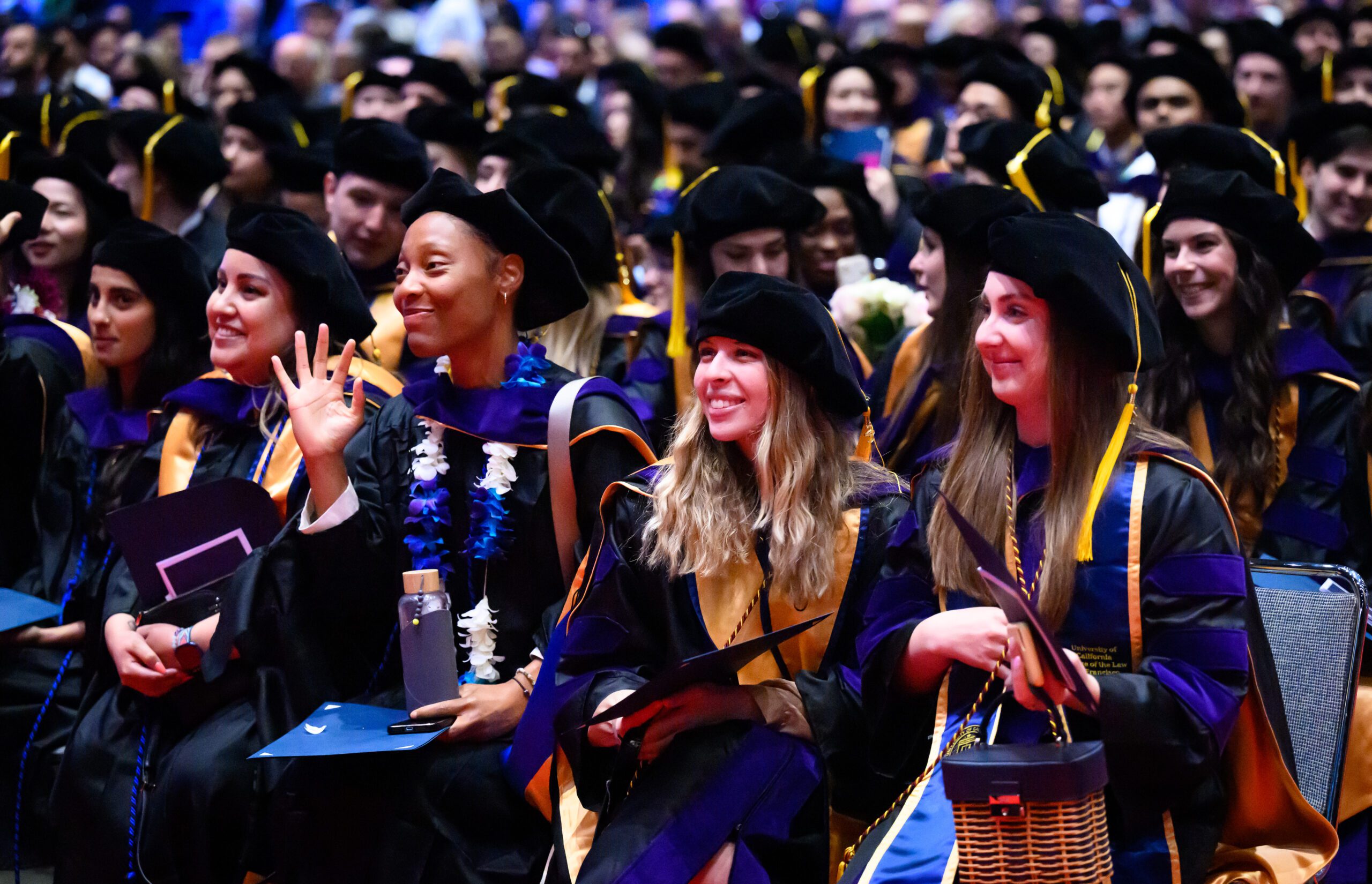 students at commencement smiling and waving