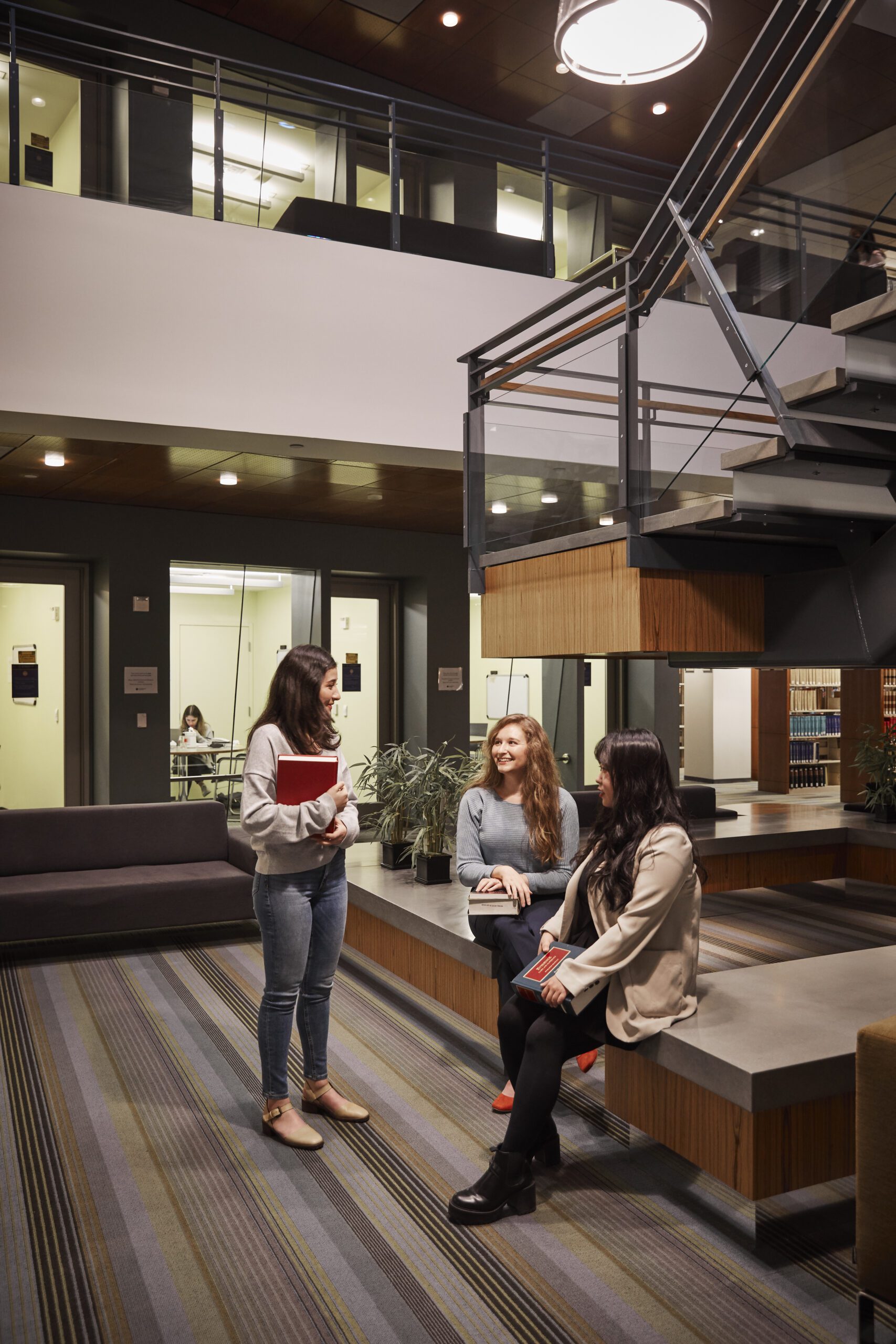 students talking in the library next to a staircase