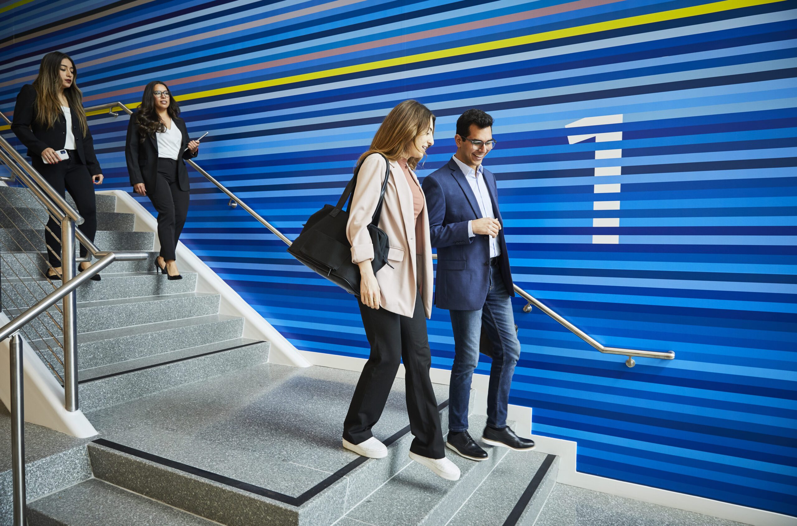 two people in professional wear walking on a staircase, with blue strip background and a number 1