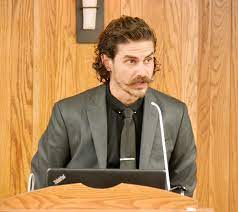 Peter Habib '23 speaks at a podium during a ceremony, wearing a suit with a tie, while a laptop is visible on the podium.