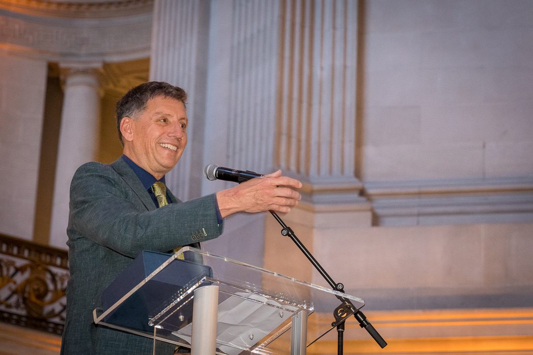 Matt Davis at a podium with a microphone inside San Francisco City Hall