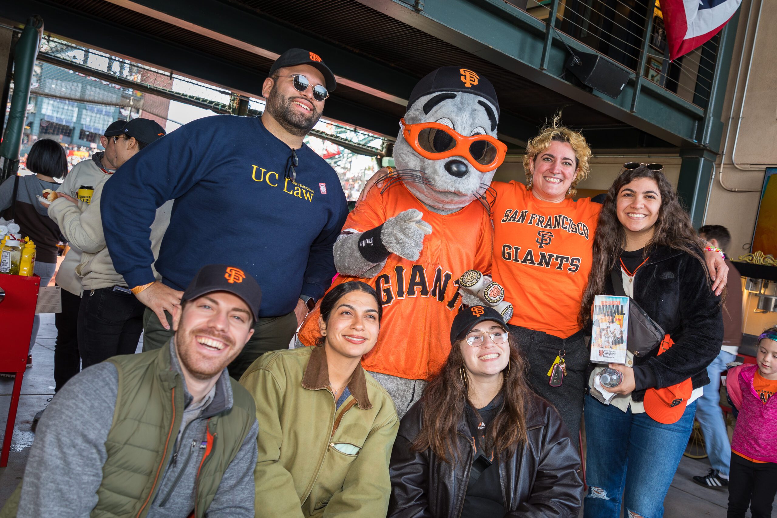 UC Law SF alumni pose with San Francisco Giants mascot Lou Seal at Oracle Park during a Spring Week game event organized by the Alumni Association.