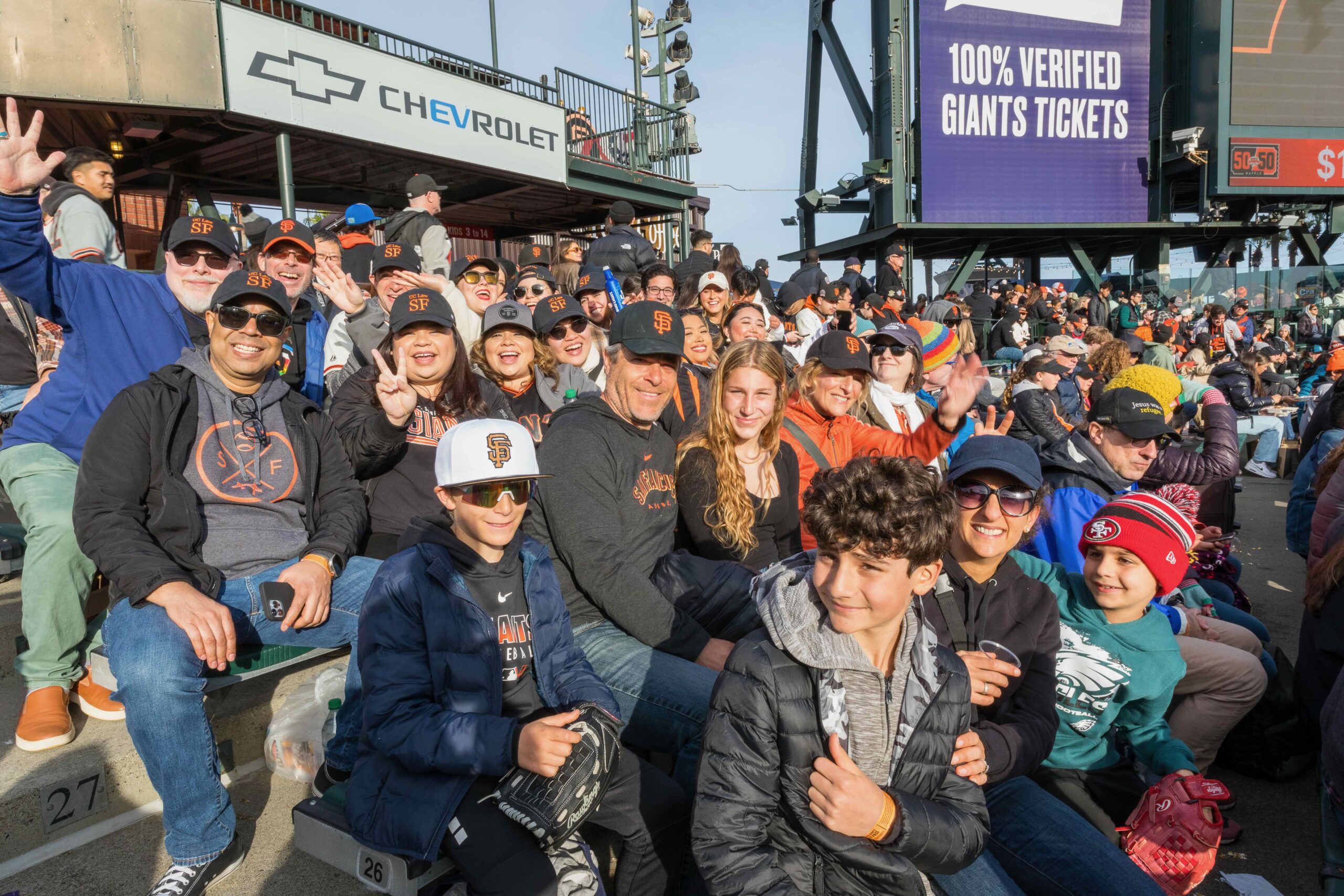 A group of UC Law SF alumni and family members sitting on the bleachers in Oracle Park