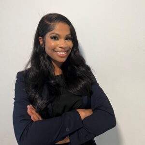 Nadiah Hadir smiling and standing in front of a white wall with her arms crossed