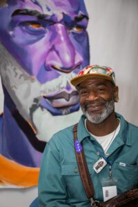 Artist Nyame Brown in front of his self-portrait in the Cotchett Law Center.