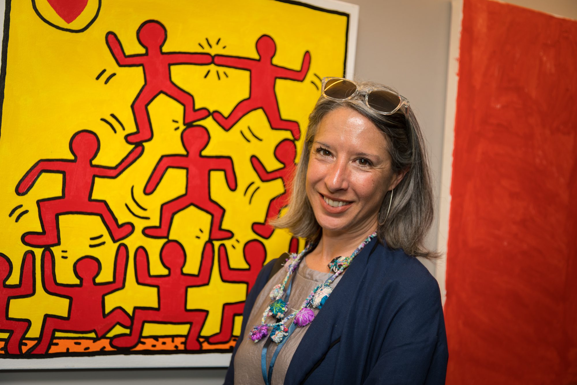 Amanda Eicher, executive director of NIAD Art Center in Richmond, California, an art studio for adult artists with disabilities, in front of a red and yellow art piece.