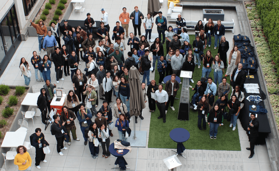 A large group of people on UC Law SF's Quad looking up and smiling at the camera