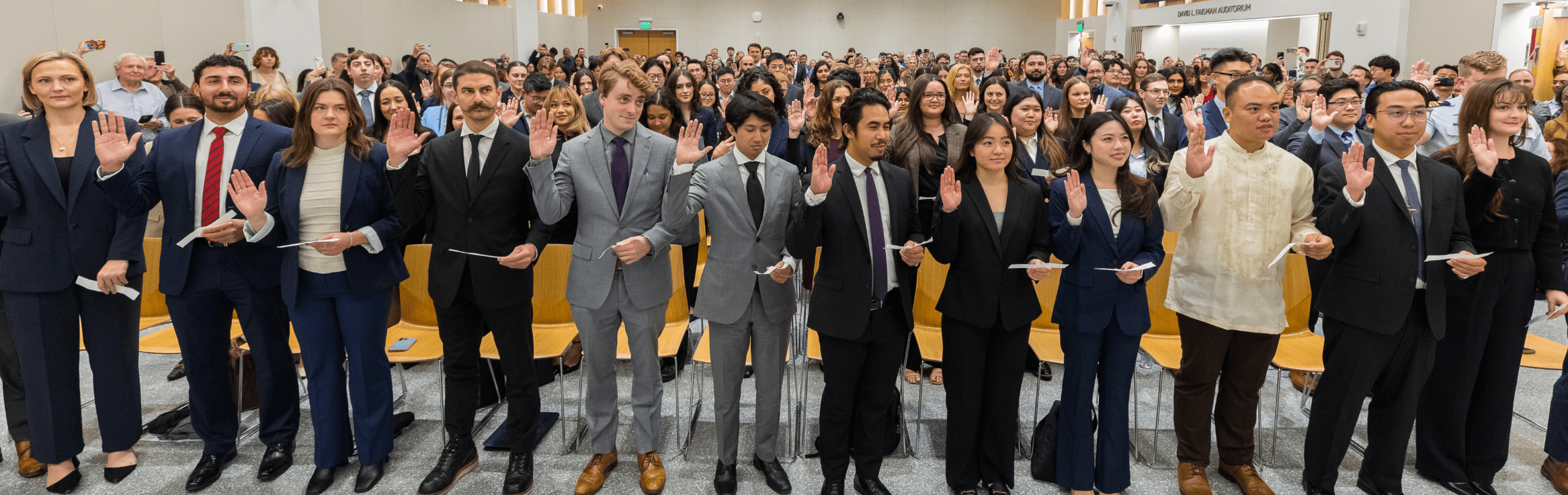 Students raising their hand in a swearing in ceremony at the 198 auditorium on campus.