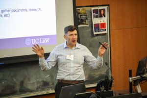 Zach Henderson speaking at the front of a classroom while standing. 