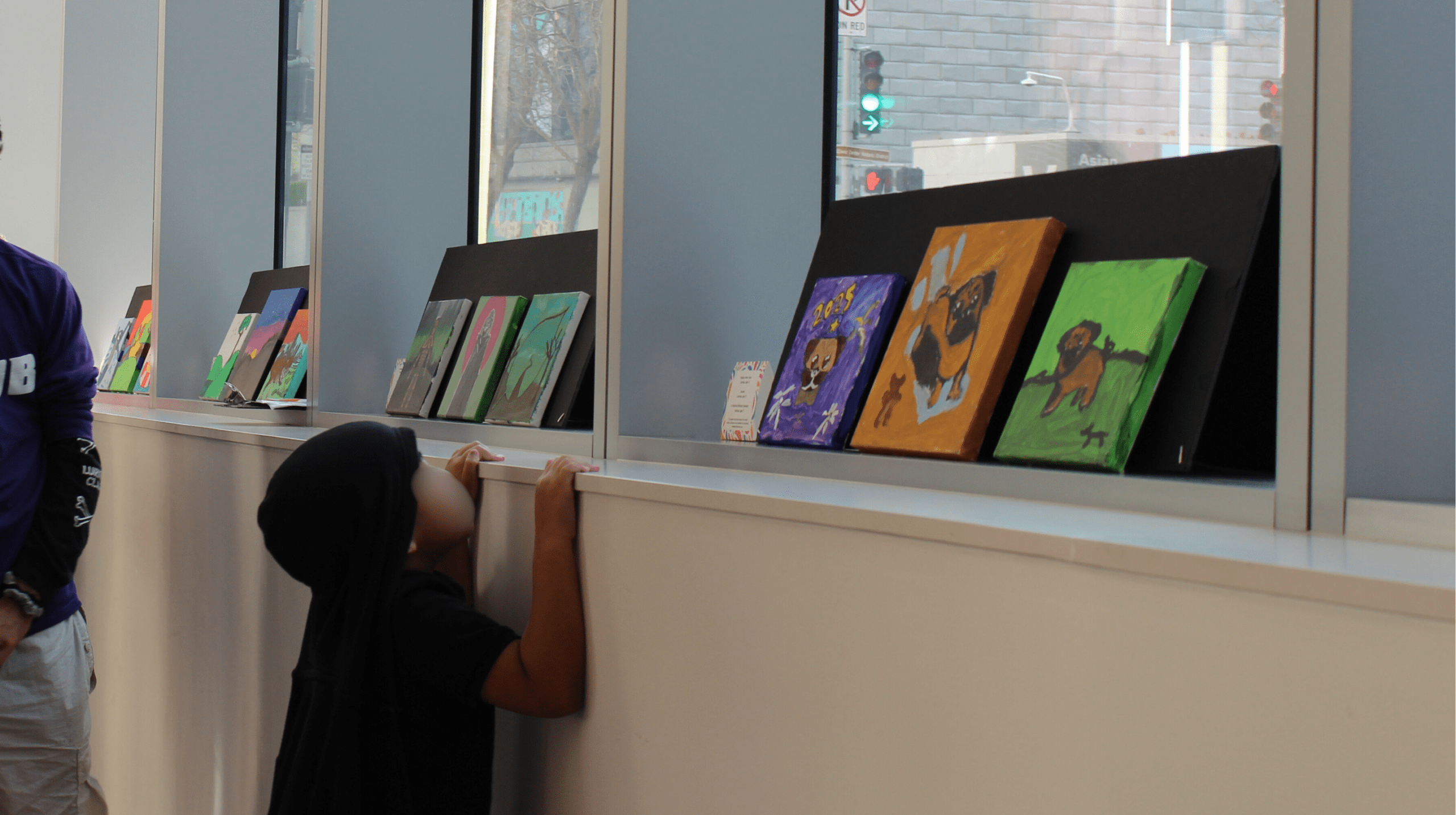 a young child looks at paintings on a shelf