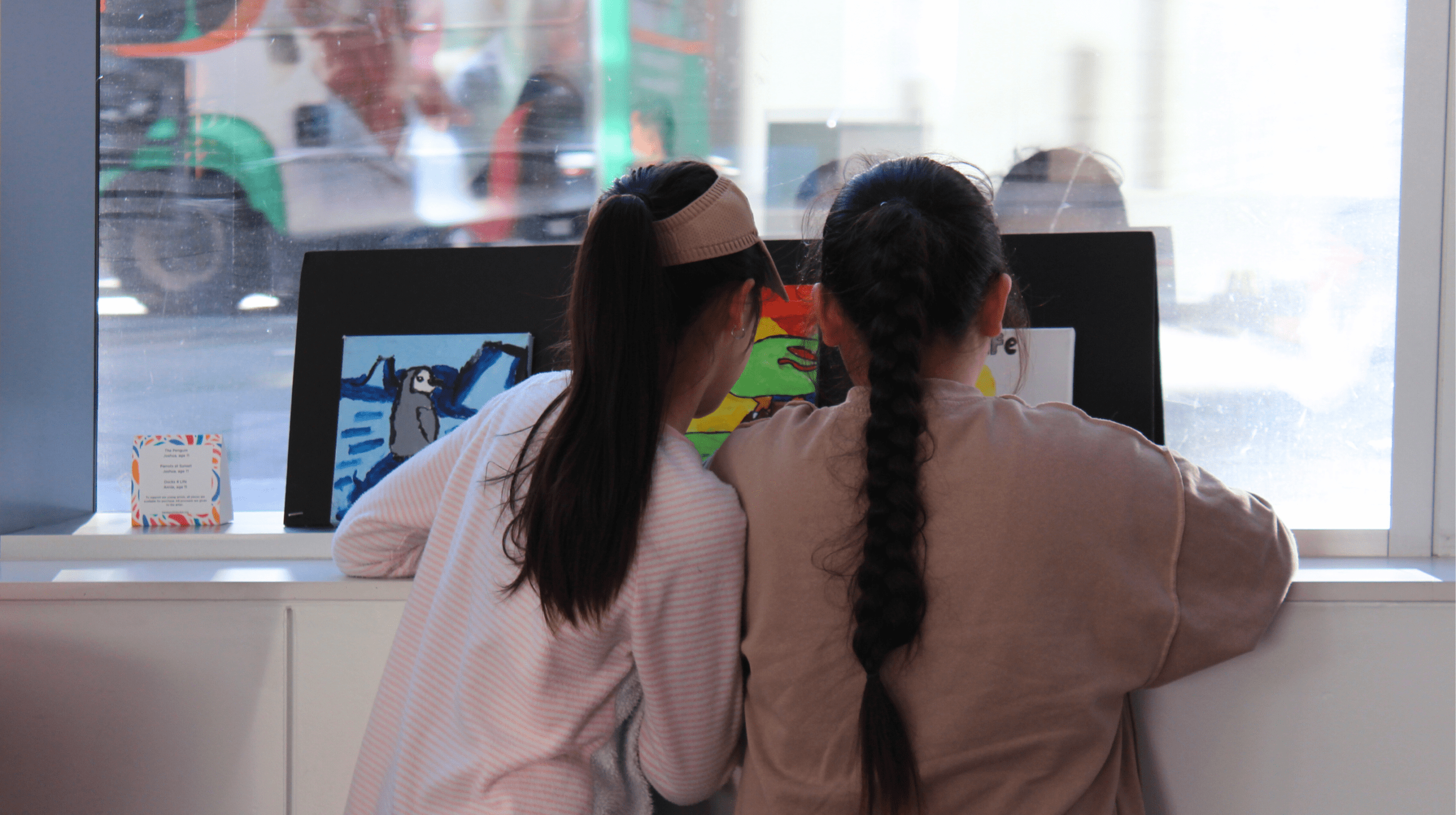 Two children look at paintings.