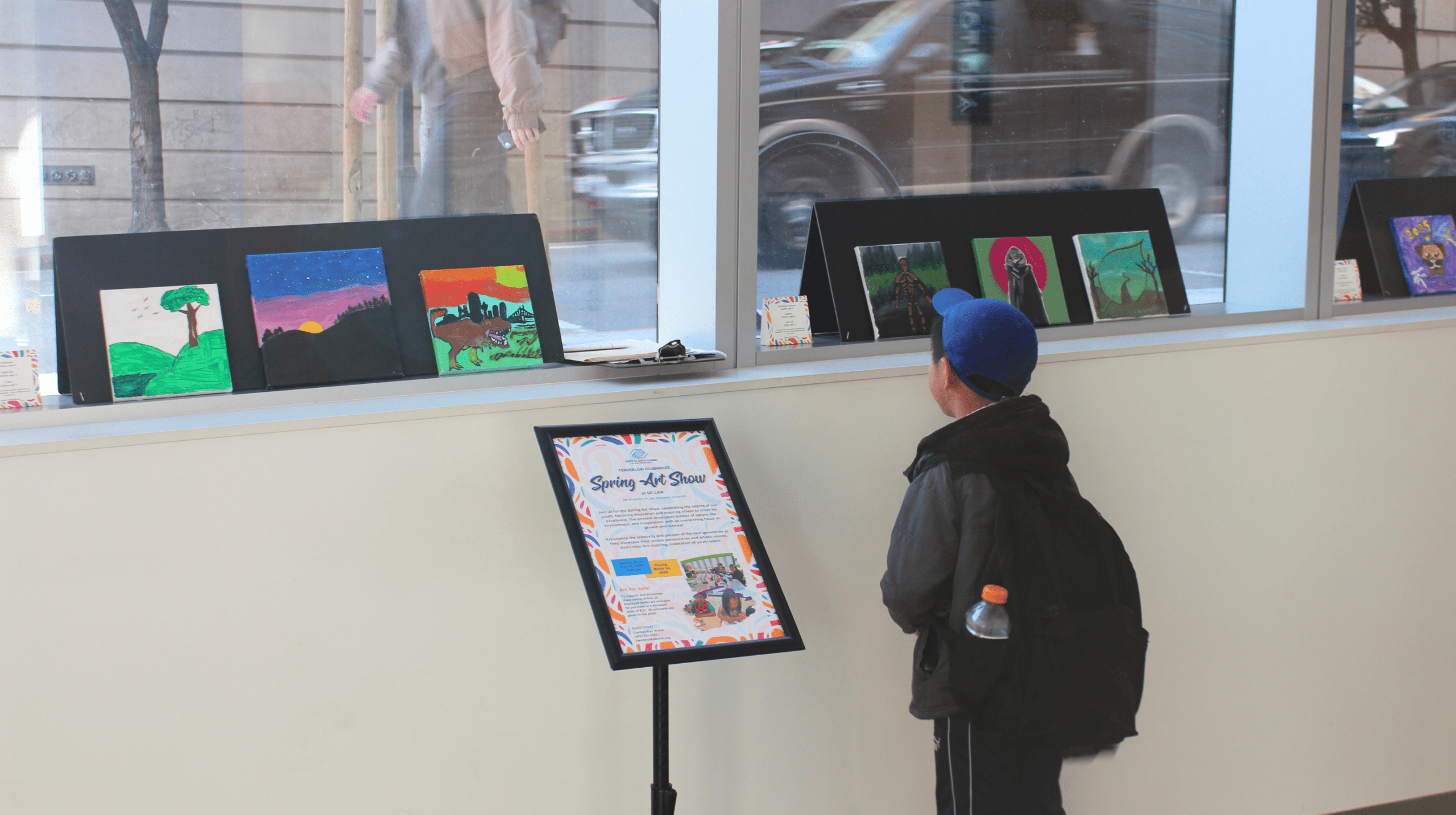 A child looks at an art show sign inside a campus building.