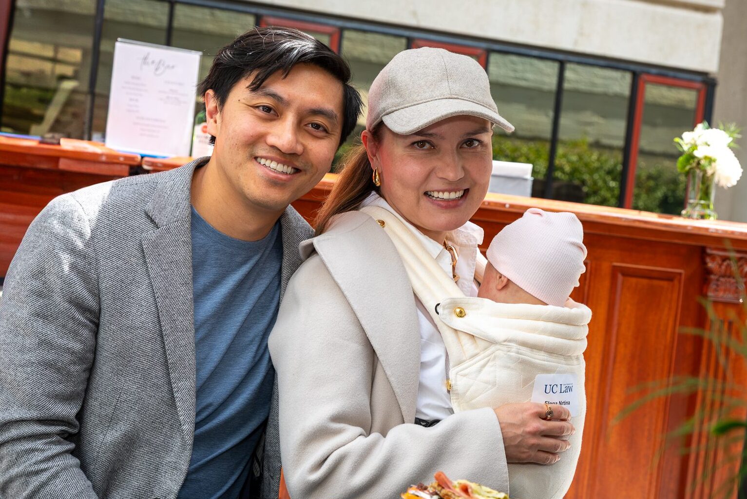 Two people pose with an infant while seated at a table.