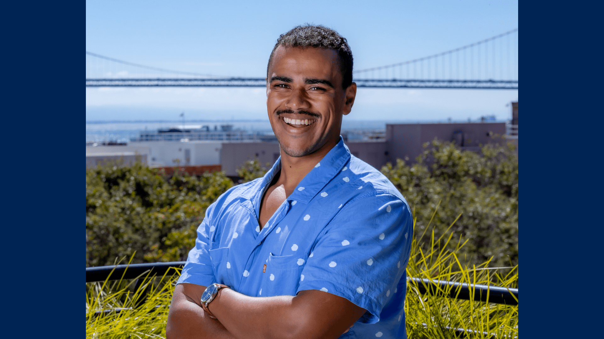 A head and shoulders photo of Myell Mergaert standing with a bridge in the background.
