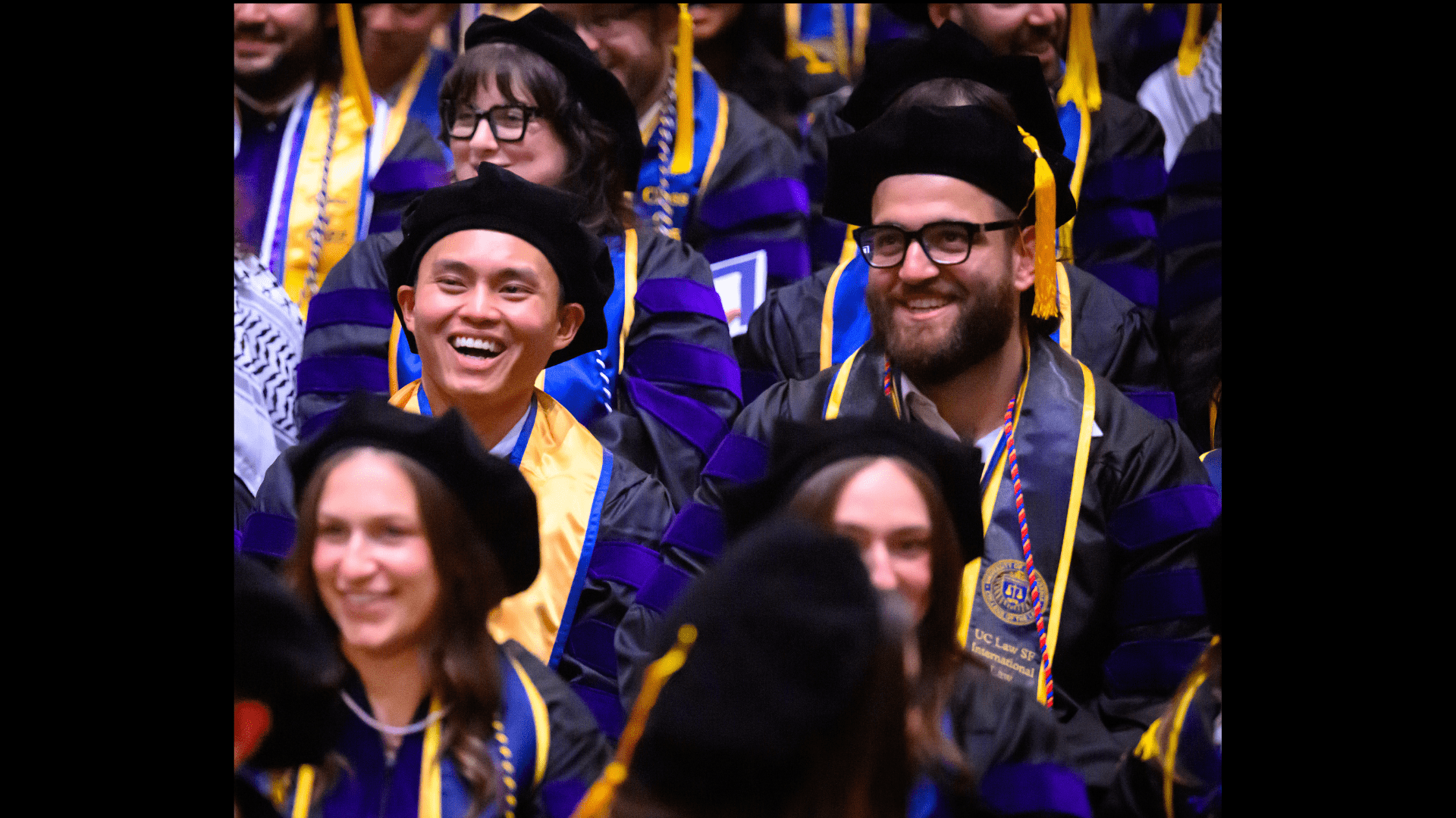 A crowd of smiling graduates with caps and gowns