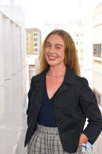 A photo of Rowan Lane smiling, wearing a black blazer.