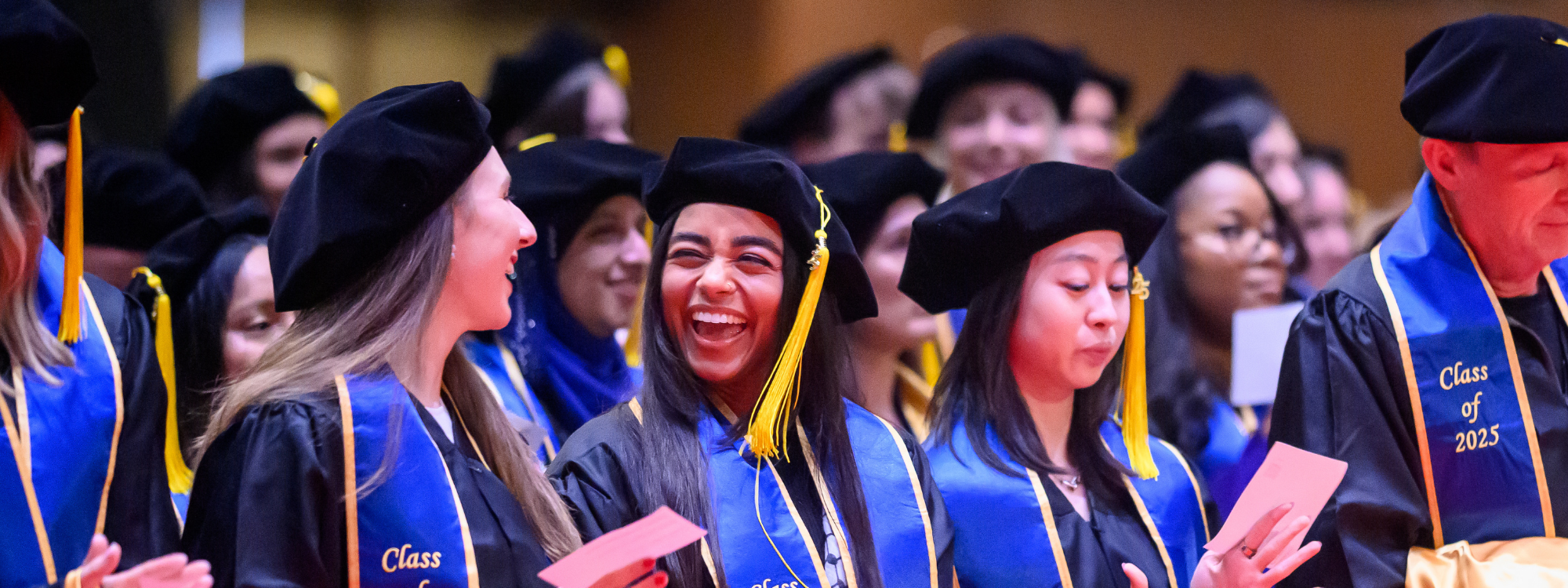 Class of 2025 graduates smiling brightly at commencement