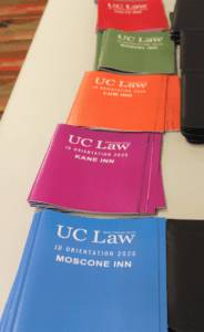 Stacks of UC Law SF J.D. Orientation guides on a table, divided by Inn