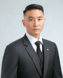 Headshot photo of Kan Lew in a dark suit and tie