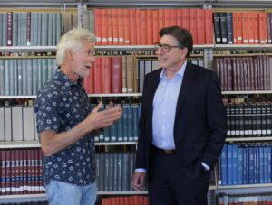 Rick Trachok and David Faigman converse in a library in front of bookshelves