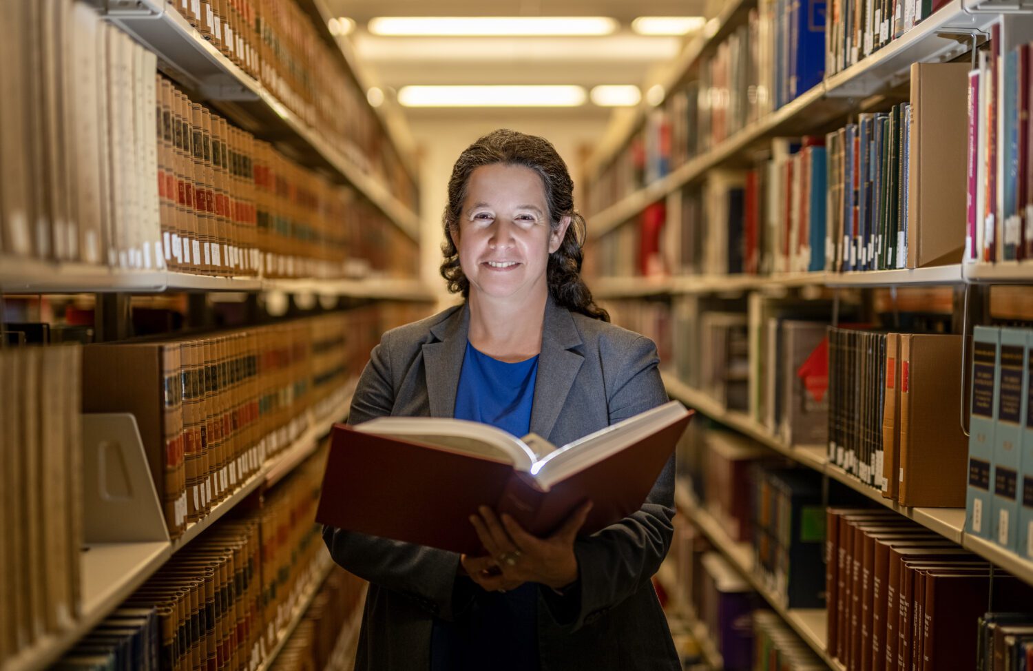 Professor Dorit Reiss poses with a book in the UC Law SF library.