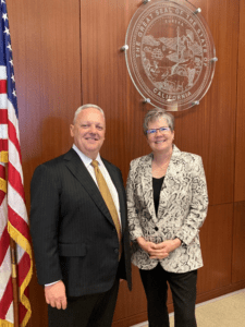 Julie Emede with Eric Geffon. They are pictured next to the American flag and the Seal of California