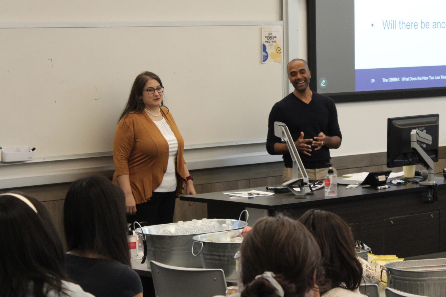 Professors Heather Field and Manoj Viswanathan stand at the front of a classroom.